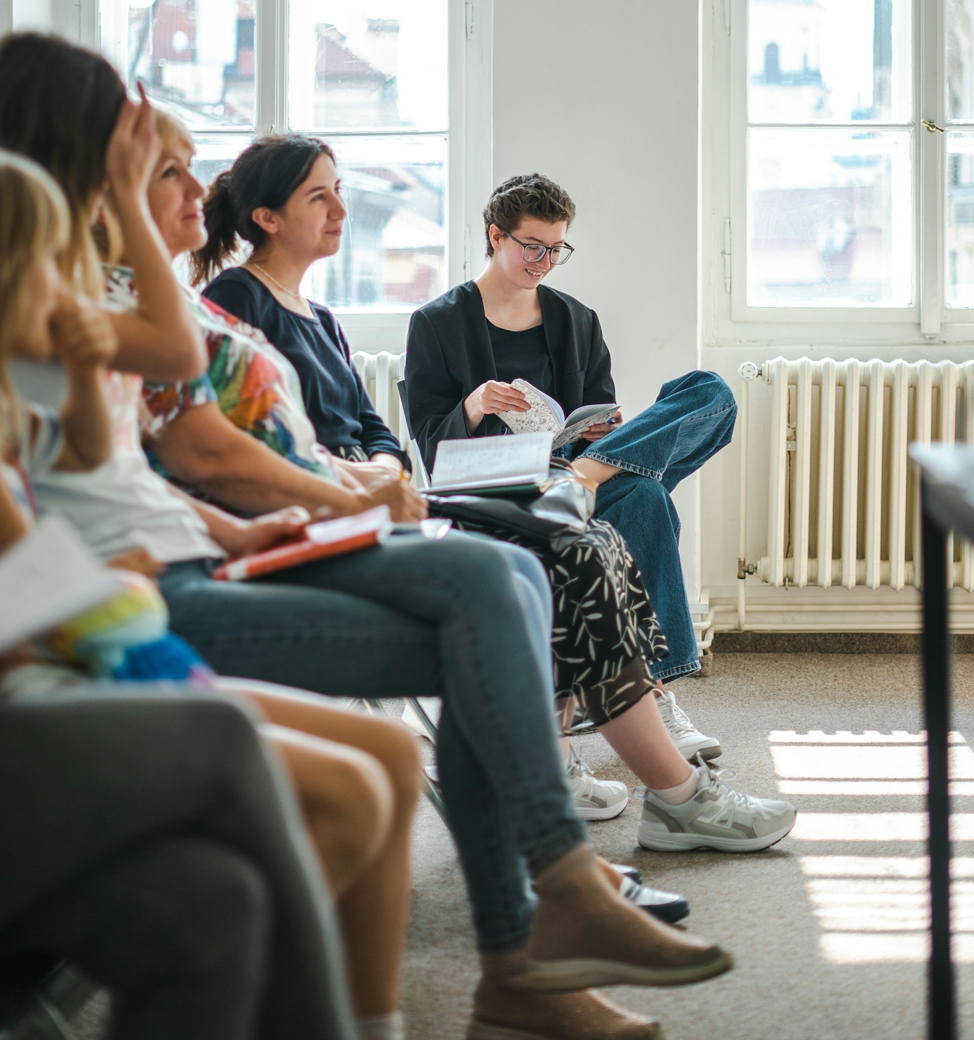 Participants seated in a bright workshop room, listening and taking notes during a professional session.
