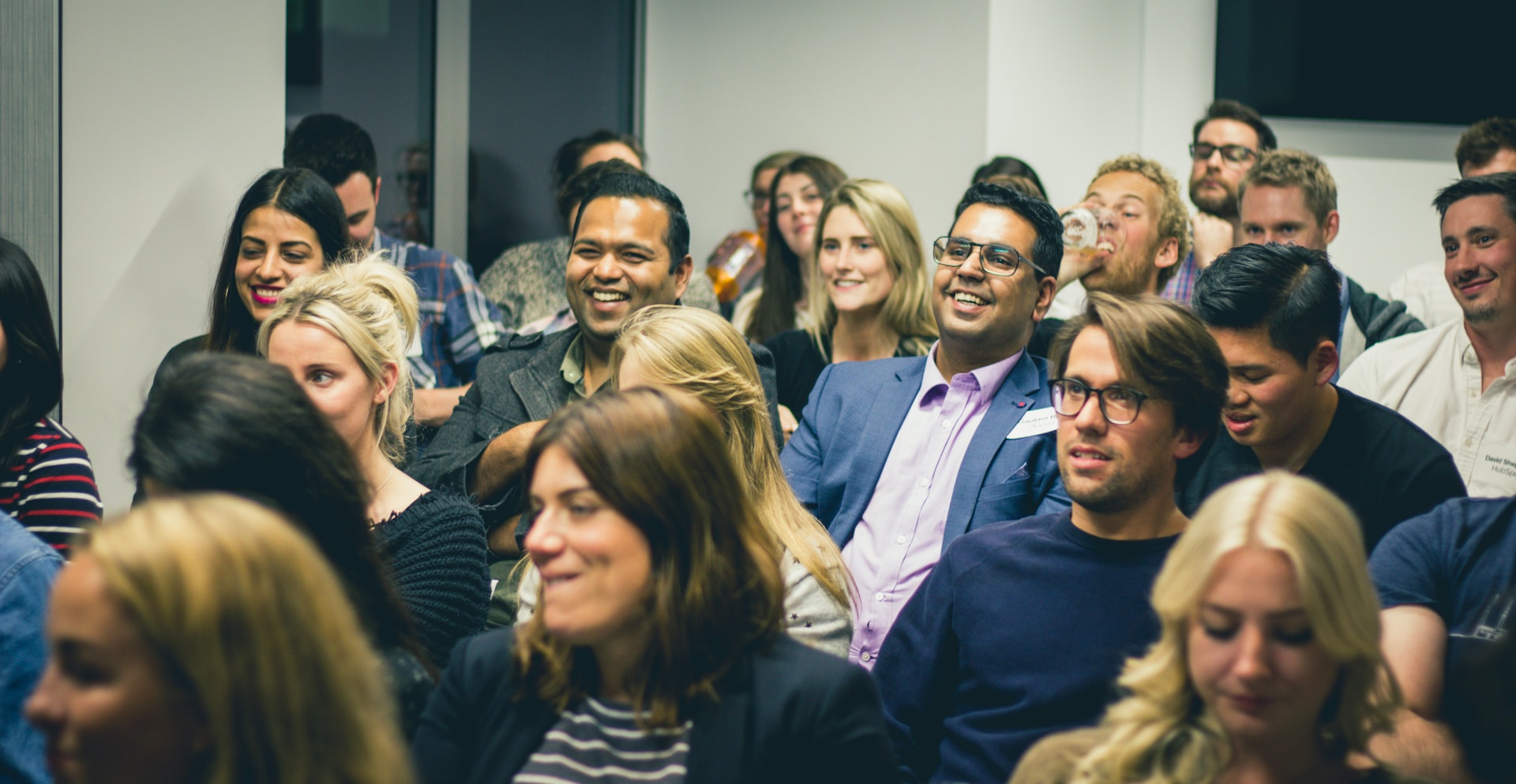 Engaged audience at a professional event A diverse audience smiling and listening during a professional event or workshop.