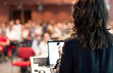 A businesswoman addressing a crowd at a conference.