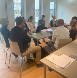 A group of healthcare professionals sits around a table in discussion during a breakout session at a neonatal care workshop.