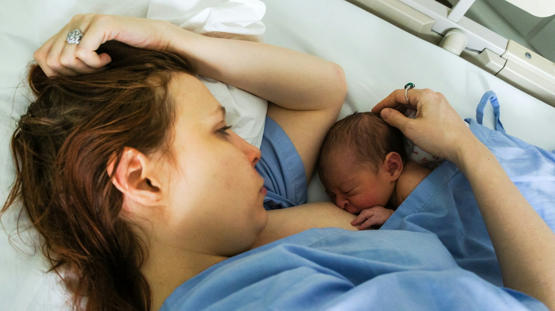 Mother breastfeeding newborn in bed